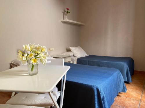 Una habitación con dos camas y un jarrón de flores sobre una mesa. en Hostal Moscatel, en Málaga