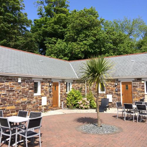 a stone building with chairs and a table and a palm tree at Trewhiddle Village cottage 42 in St Austell