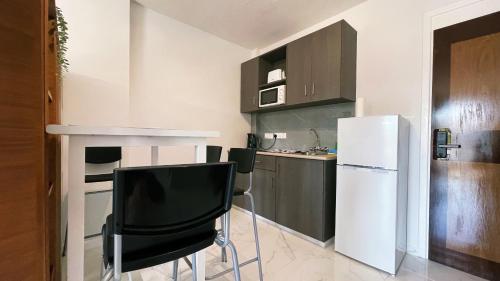 a kitchen with a white refrigerator and black chairs at Fotoxenia Luxury Apts in Paralimni