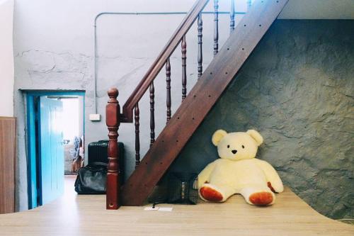 a teddy bear sitting on the floor under a staircase at Taipei Jinguashi Cloud Mountain Homestay B&B in Jiufen