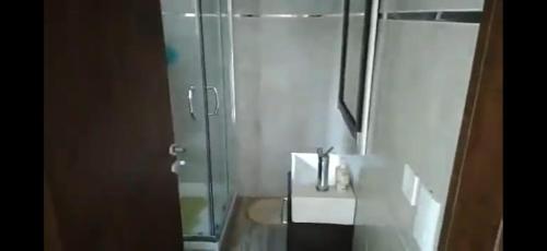 Un baño con ducha de cristal y lavabo. en Balcón del Bosque, en Monte Hermoso