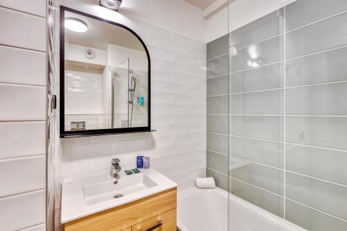 La salle de bains blanche est pourvue d'un lavabo et d'un miroir. dans l'établissement Appart'City Confort Paris Clichy - Mairie, à Clichy