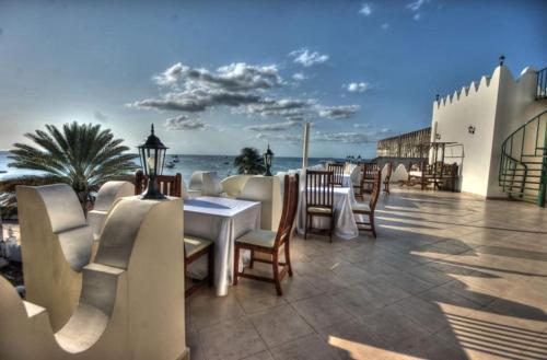 a restaurant with tables and chairs and the ocean at The Seyyida Hotel and Spa in Zanzibar City