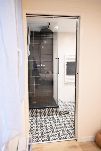 une porte en verre menant à une salle de bains dotée de carrelage noir et blanc. dans l'établissement PERLEZENN VONTROULEZ (T2 45m2), à Morlaix