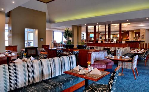 un restaurante con mesas y sillas y un bar en City Lodge Hotel Bloemfontein, en Bloemfontein