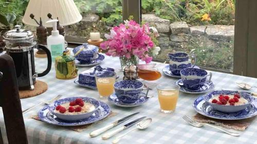 una mesa con platos azules y blancos de comida y bebida en The Potting Shed, self contained, detached retreat in Shapwick village, en Shapwick