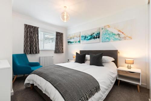 a bedroom with a bed and a blue chair at 25 Coedrath Park - Sea Views from Balcony, Short Walk to Beach, Parking in Saundersfoot