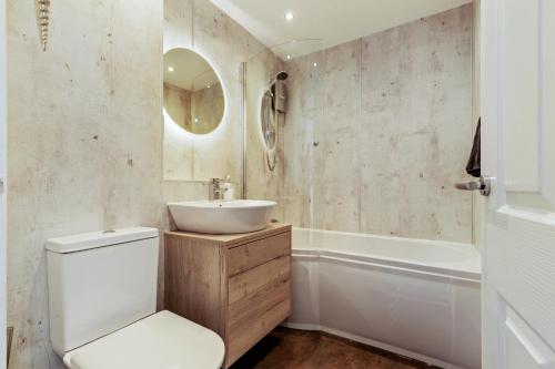 a bathroom with a toilet and a sink and a tub at 25 Coedrath Park - Sea Views from Balcony, Short Walk to Beach, Parking in Saundersfoot