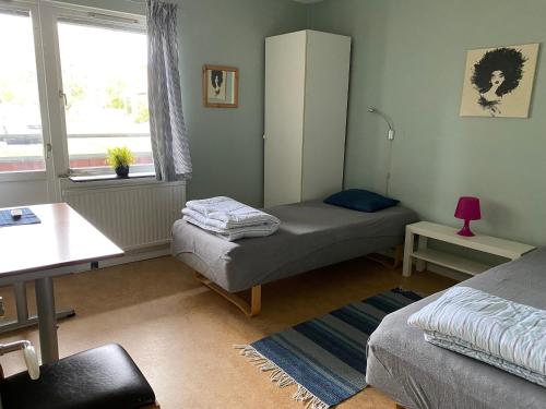 a bedroom with two beds and a table and a window at Borlänge Vandrarhem & Turistlägenheter in Borlänge