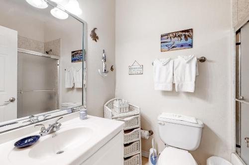 a bathroom with a sink and a toilet and a mirror at Golden Gate Getaway in South Padre Island