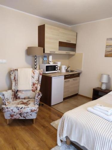 a bedroom with a bed and a chair and a kitchen at Savona Świnoujście in Świnoujście