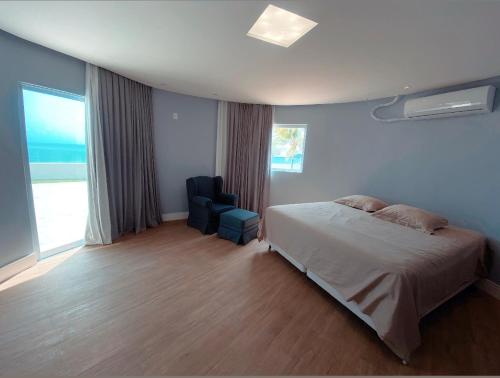 a bedroom with a bed and a chair and a window at Luxo e pé na areia in Parnamirim