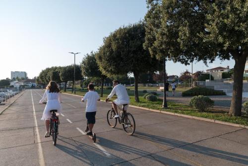 a group of people riding bikes down a sidewalk at Rocca Riviera Umag Luxury Apartments in Umag
