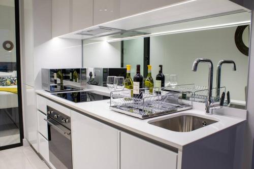 a kitchen with a sink and a counter with wine glasses at Modern 1 Bedroom Executive Apartment in Waterfall in Midrand