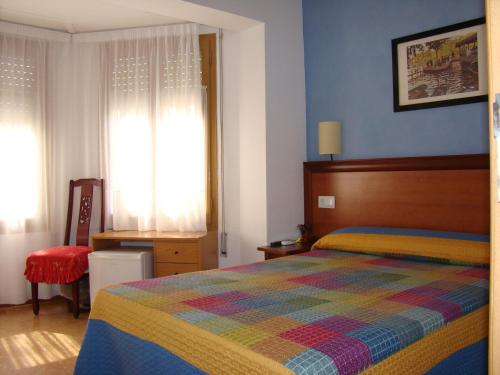 um quarto com uma cama com um cobertor colorido em Hostal Platja em Cambrils