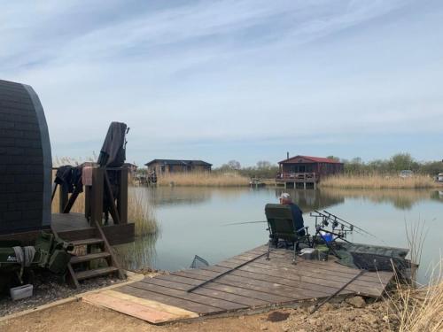 een man op een stoel op een steiger op een meer bij Lakeside Fishing Pods in Boston