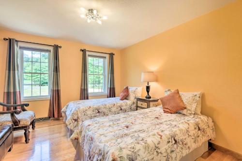 a bedroom with two beds and a chair and two windows at Granby Home with Deck Less Than half Mi to Aldrich Lake! in Granby