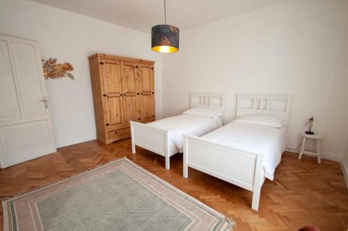 1 Schlafzimmer mit 2 weißen Betten und Holzboden in der Unterkunft Casa Sass in Trient