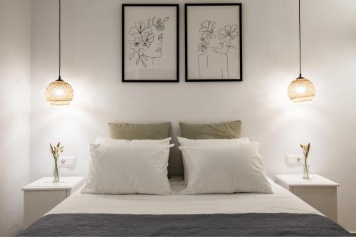 a bedroom with three pictures above a bed with white pillows at Uncle John's Guesthouse in Skopelos Town