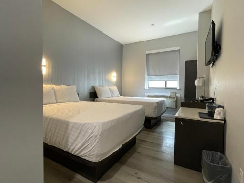 Cette chambre comprend deux lits et une télévision. dans l'établissement King Hotel Brooklyn Sunset Park, à Brooklyn
