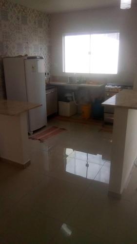 une cuisine avec un réfrigérateur blanc et une fenêtre dans l'établissement Casa do sol, à Arembepe