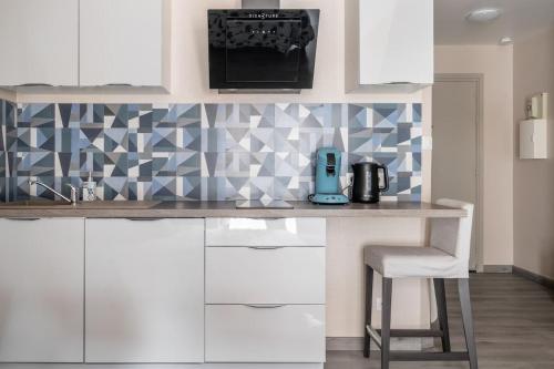 une cuisine avec des placards blancs et un comptoir avec une chaise dans l'établissement Studio centre historique, place de la réunion, à Mulhouse