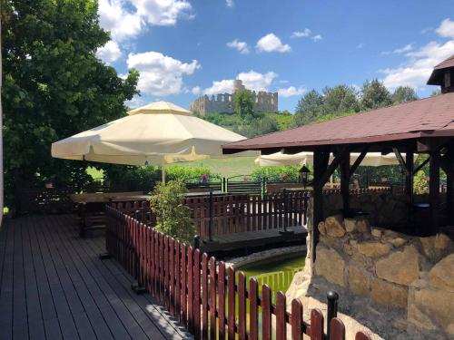 a patio with tables and umbrellas and a pond at Zajazd Podzamcze in Olkusz