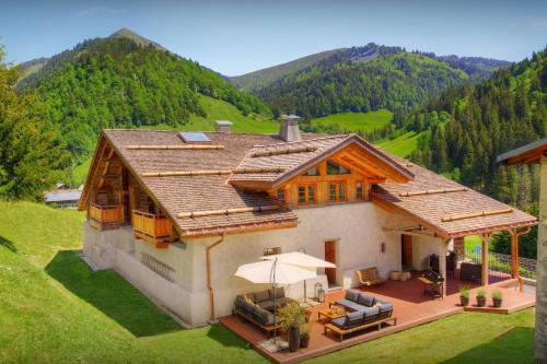 a house in the middle of a field with mountains at Chalet Goville - OVO Network in La Giettaz