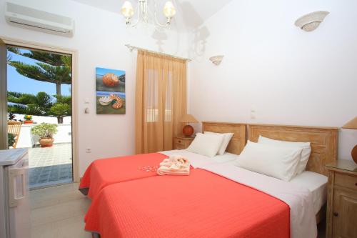 - une chambre avec un lit et une couverture rouge dans l'établissement Pension Anna, à Náoussa