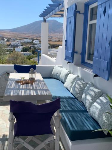 una mesa y un banco en un balcón con persianas azules en Irenes 2floor maisonette en Piso Livadi