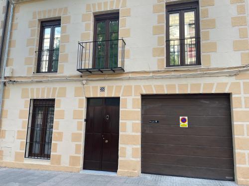 two garage doors on a brick building with windows at Suite Lugo in Úbeda