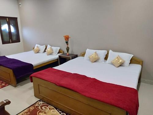 2 Betten in einem Zimmer mit einer roten und weißen Decke in der Unterkunft Hotel Jungle Palace Resort in Umariā