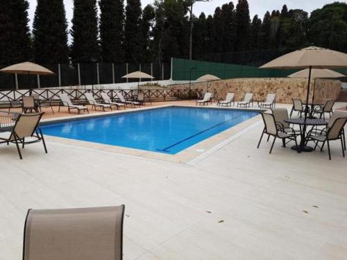 a swimming pool with chairs and tables and umbrellas at Loft Res Pedra Azul - hospedagem nas montanhas in Pedra Azul