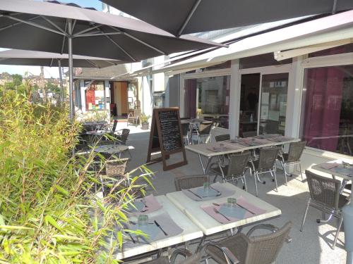 an outdoor patio with tables and chairs and umbrellas at Le Gue de Genes in Ambrieres Les Vallees