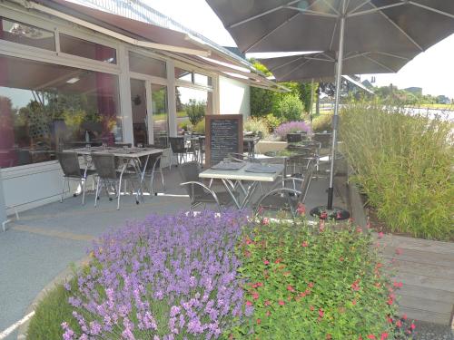 an outdoor patio with tables and flowers and an umbrella at Le Gue de Genes in Ambrieres Les Vallees