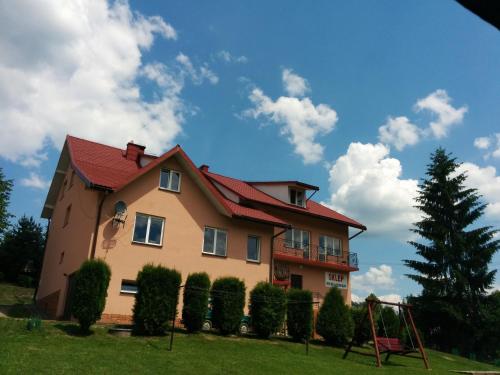 dom z czerwonym dachem i huśtawką w obiekcie Apartament w Bieszczadach w Wołkowyi