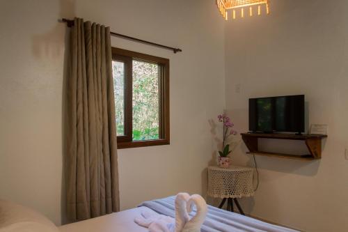 a bedroom with a bed and a tv and a window at Morada do Gabriel in Guarda do Embaú