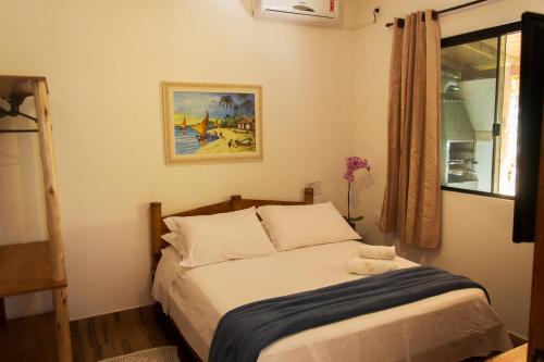 a bedroom with a bed with a picture on the wall at Morada do Gabriel in Guarda do Embaú