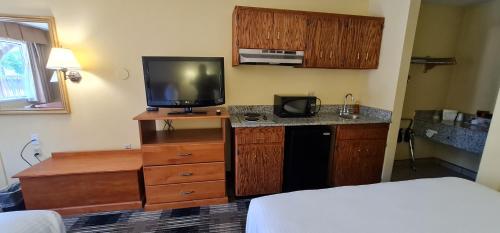 a hotel room with a bed and a tv and a kitchen at Oakridge Inn & Suites in Oakridge