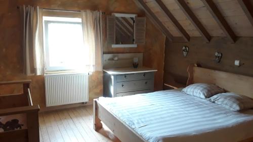 a bedroom with a bed and a dresser and a window at Ma baraque de vacances in Butgenbach