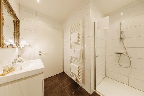 a white bathroom with a shower and a sink at Pfeiler's Bürgerstüberl - Hotel in Feldbach