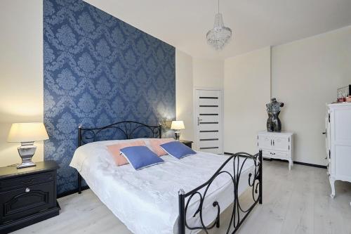 1 dormitorio con cama y pared azul en Art Apartment Szczawno Zdrój en Szczawno-Zdrój
