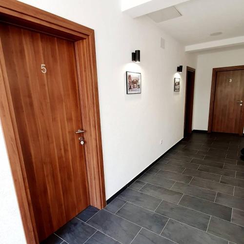 a hallway with a wooden door and a tile floor at Apartmani Brko in Kotor-Varoš
