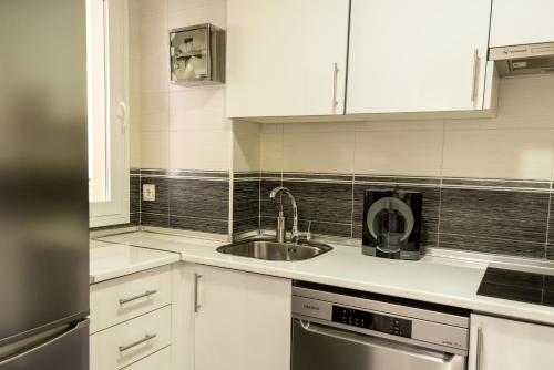 a kitchen with white cabinets and a sink at Lindo apartamiento Tivoli in Arroyo de la Miel