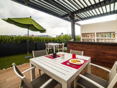 een witte tafel en stoelen op een patio met een parasol bij Hotel Nube in Puebla