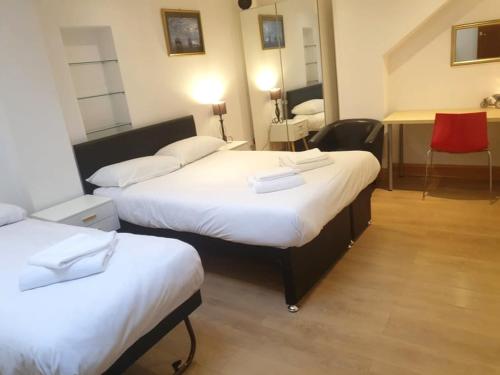una habitación de hotel con 2 camas y una silla roja en Hastings Pad en Hastings