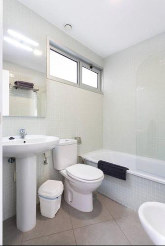 a bathroom with a toilet and a sink and a tub at Modern seafront flat with a private garage in El Médano