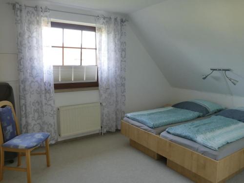 ein Schlafzimmer mit einem Bett, einem Fenster und einem Stuhl in der Unterkunft Cozy Apartment located in Rovershagen with Garden in Rövershagen