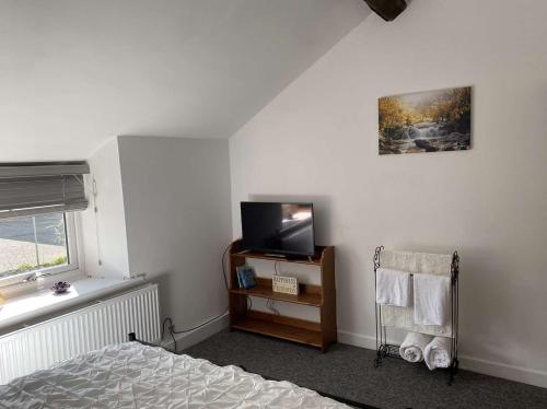 Rhos cottage Ruthin في روثين: غرفة نوم مع سرير وتلفزيون على الحائط