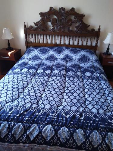 a blue and white quilt on a bed with two lamps at Casa en algarrobo in Algarrobo